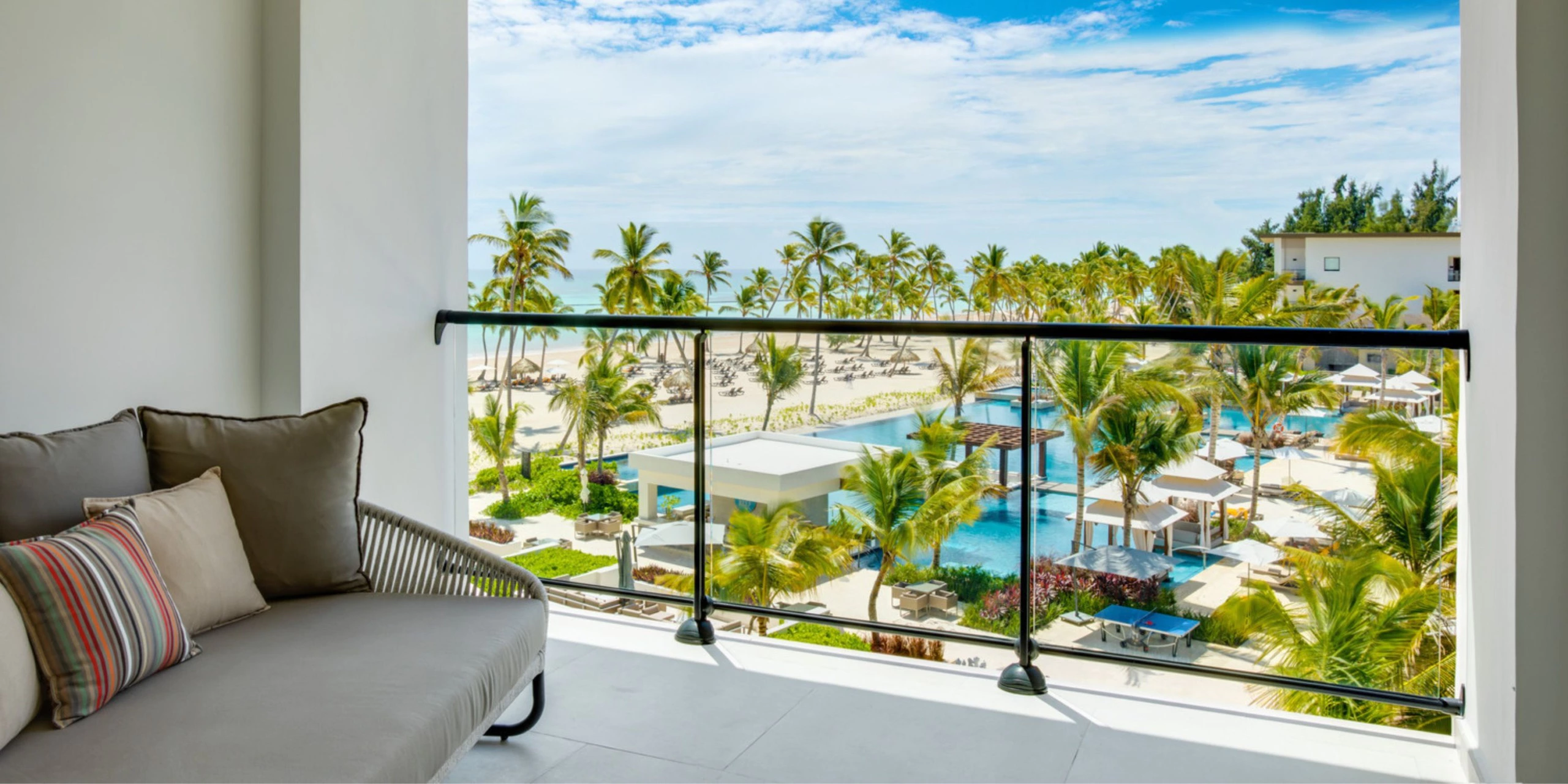Private balcony with views of pools, palm trees, and the Caribbean Sea at Hyatt Zilara Cap Cana.