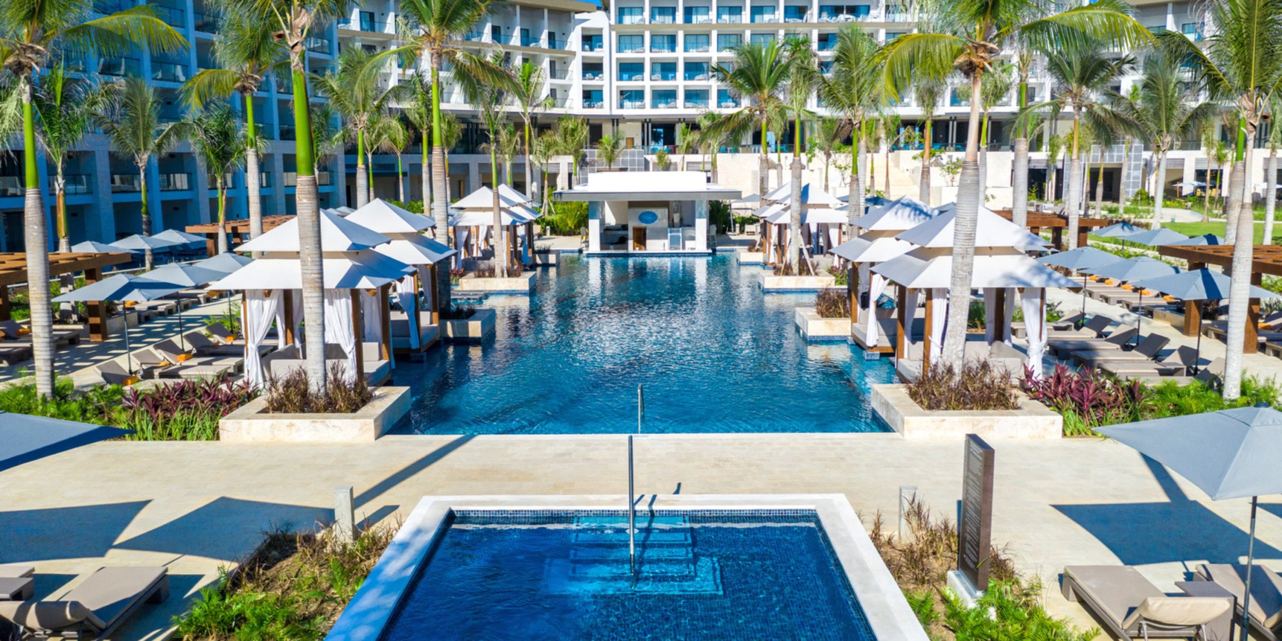 Expansive resort pools surrounded by palm trees and luxury cabanas at Hyatt Zilara Cap Cana.
