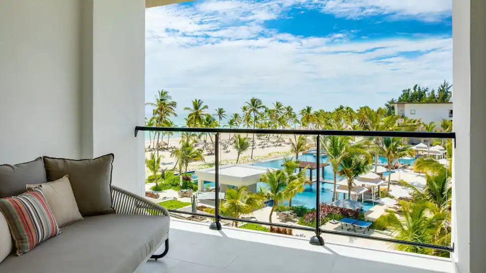 Ocean View Junior Suite King balcony overlooking pools, palm trees, and the Caribbean Sea at Hyatt Zilara Cap Cana.